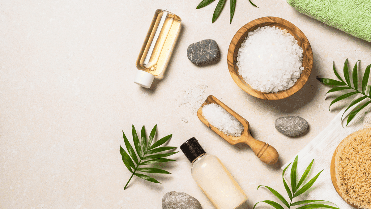 Spa-tuotteen koostumus, jossa palmunlehtiä, pyyhkeitä ja kosmeettisia kiviä tasaisella näytöllä Spa-tuotteen koostumus, jossa palmunlehtiä, pyyhkeitä ja kosmeettisia kiviä tasaisella näytöllä