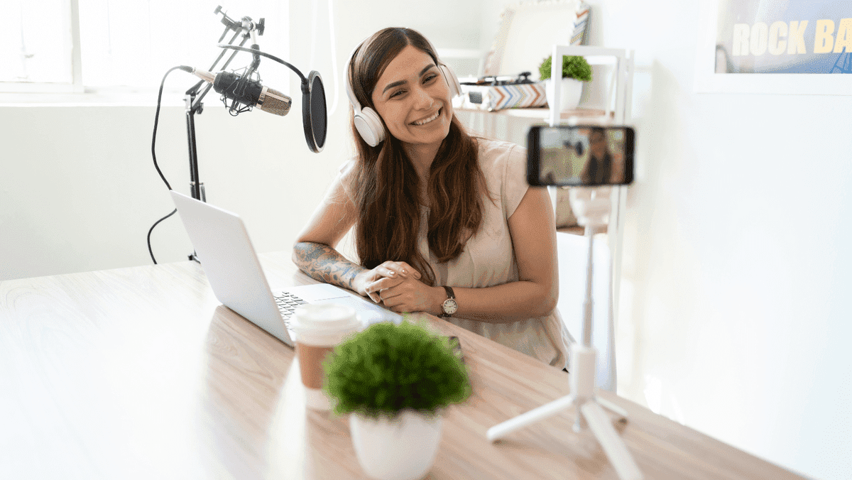 Influencer creând un videoclip cu laptop alb pe o masă Influencer creând un videoclip cu laptop alb pe o masă