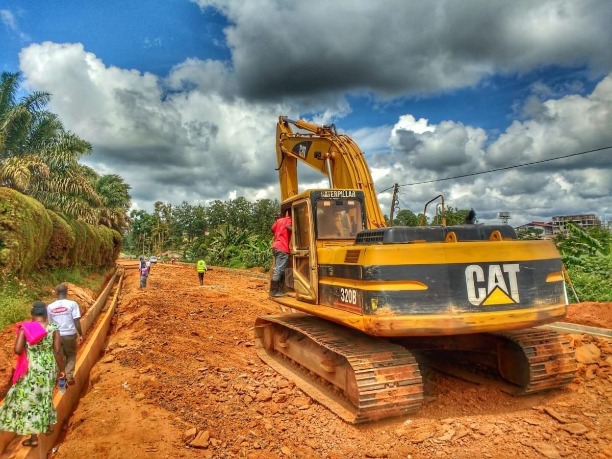 A digger breaks up the road on the Uganda Marathon route in Masaka District as locals walk by along the gutter A digger breaks up the road on the Uganda Marathon route in Masaka District as locals walk by along the gutter