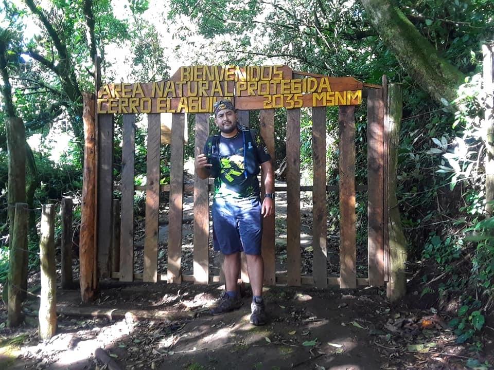 a trail runner poses for a photo at the entrance of Cerro El Aguila in El Salvador before a trail run a trail runner poses for a photo at the entrance of Cerro El Aguila in El Salvador before a trail run