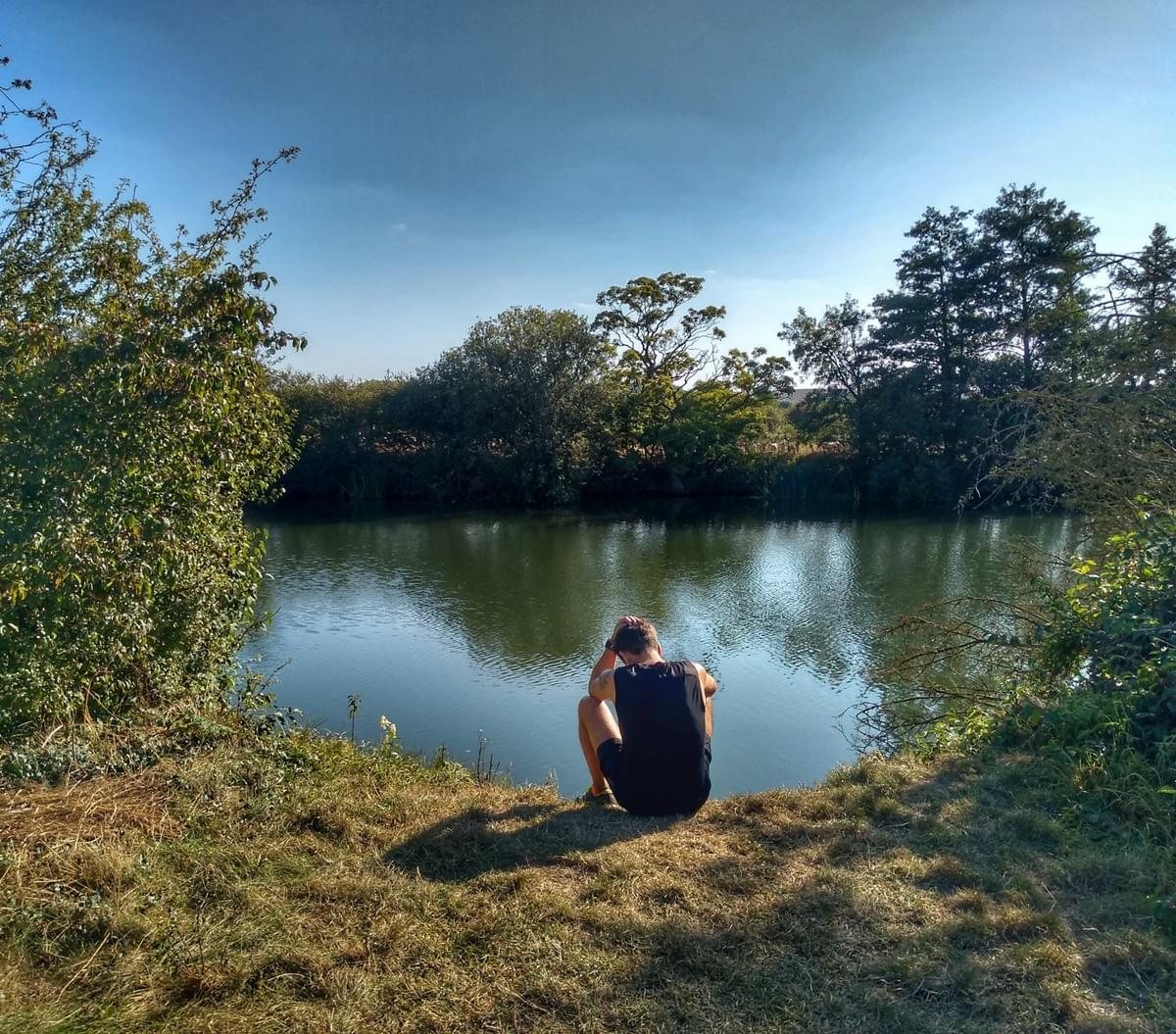 Runner pausing for rest beside the river on a grassy section of the Thames Path National Trail route in Dorchester Runner pausing for rest beside the river on a grassy section of the Thames Path National Trail route in Dorchester