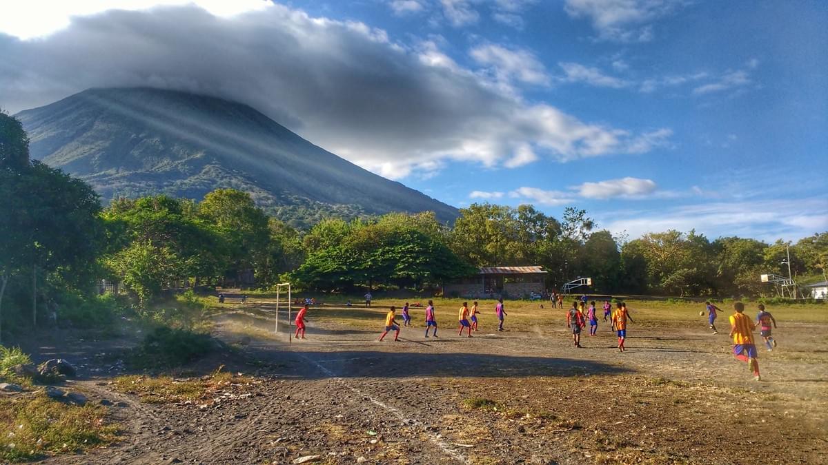 A local football match on a dirt pitch in the shadow of a volcano A local football match on a dirt pitch in the shadow of a volcano