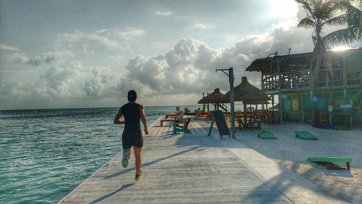 A runner on a boardwalk extending into the sea on the Caribbean island of Caye Caulker, Belize A runner on a boardwalk extending into the sea on the Caribbean island of Caye Caulker, Belize