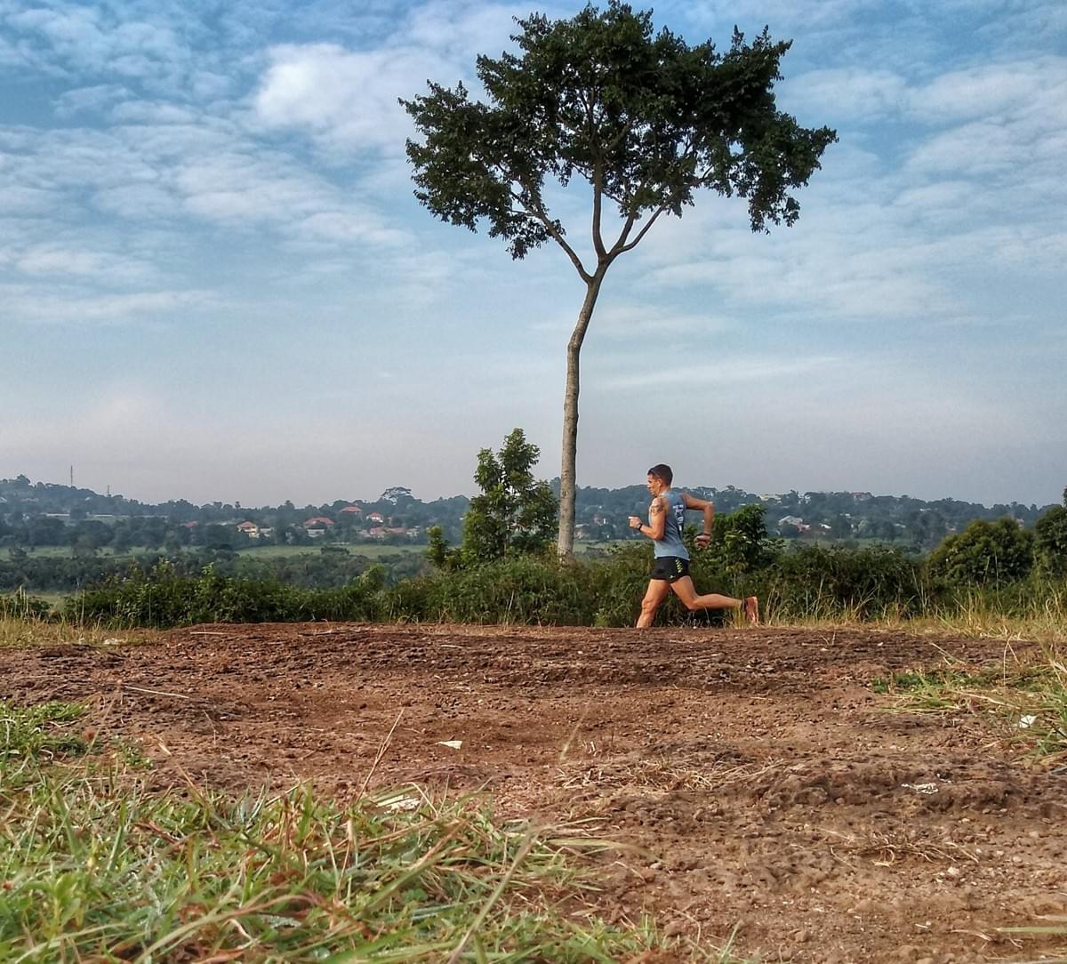A solo trail runner runs past a large tree in Entebbe, Uganda A solo trail runner runs past a large tree in Entebbe, Uganda