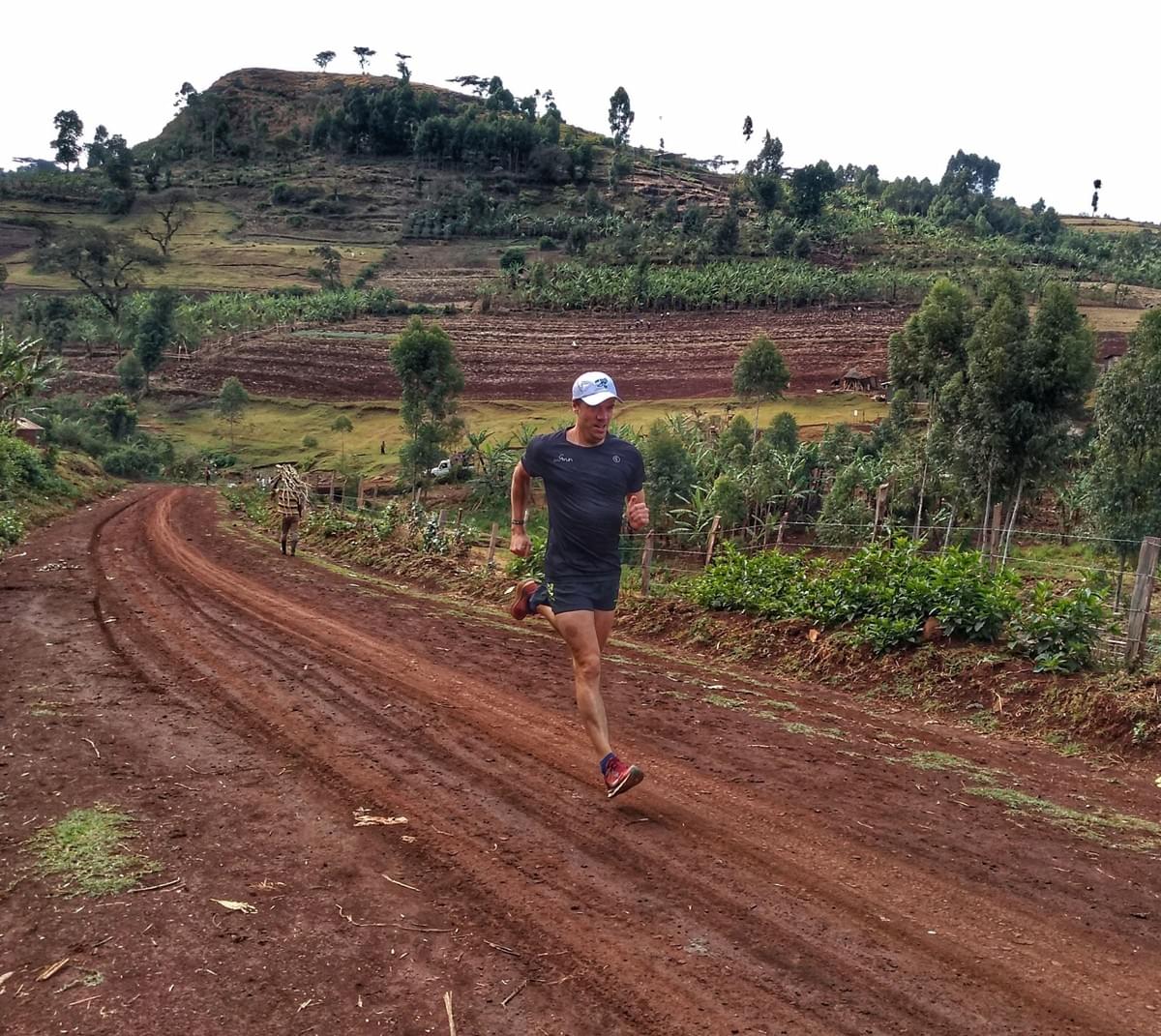 Running along a muddy dirt trail beside a local farmer in Kapchorwa, Uganda Running along a muddy dirt trail beside a local farmer in Kapchorwa, Uganda