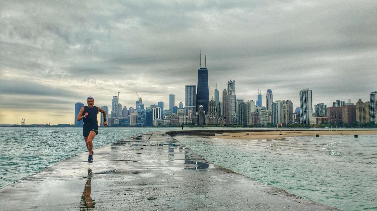 A runner runs the rain-soaked pier out onto Lake Michigan in front of the Chicago city skyline A runner runs the rain-soaked pier out onto Lake Michigan in front of the Chicago city skyline