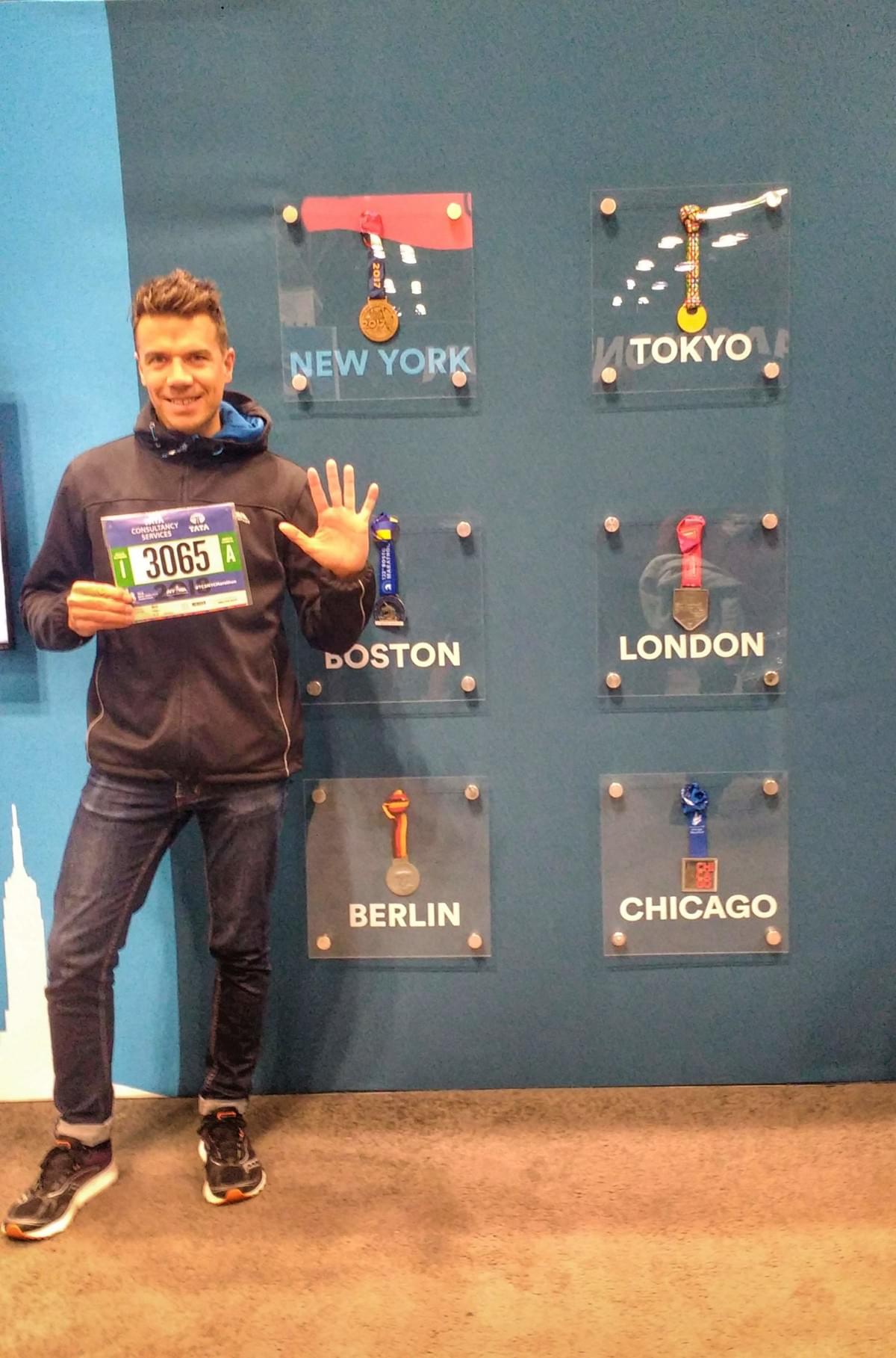 A runner holds his race number in front of the six world marathon major medals at the New York Marathon expo A runner holds his race number in front of the six world marathon major medals at the New York Marathon expo