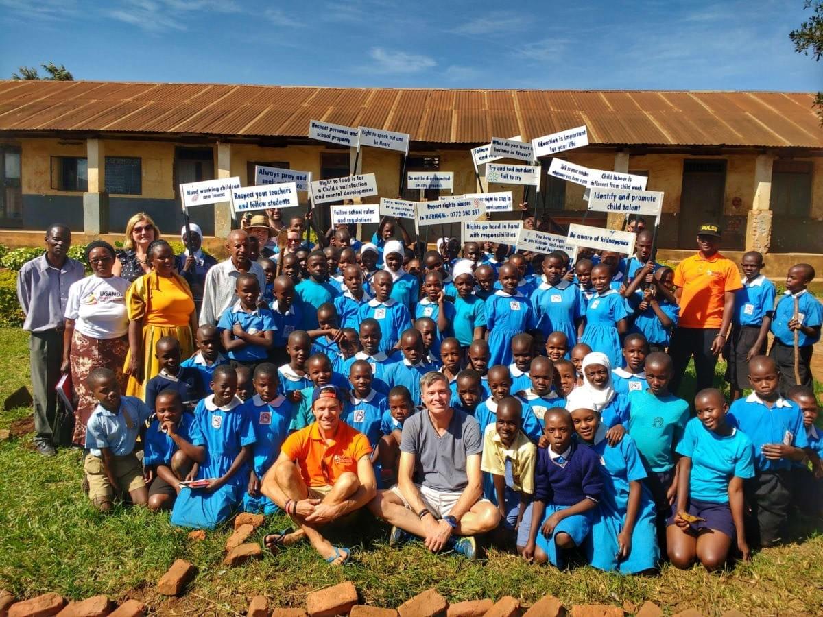Uganda Marathon runners pose for a photo with local schoolchildren after making educational signs for human rights education Uganda Marathon runners pose for a photo with local schoolchildren after making educational signs for human rights education
