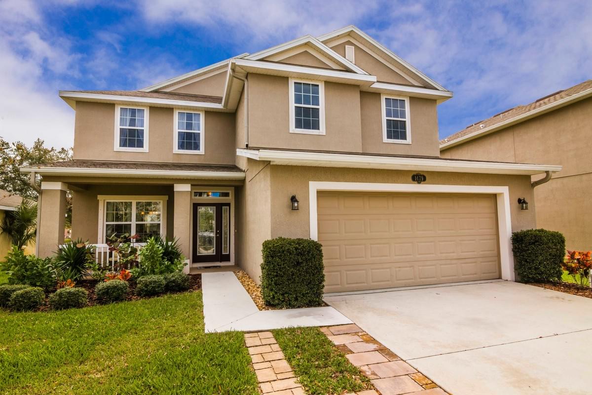 Tan 2 story home with white accents and black door Tan 2 story home with white accents and black door