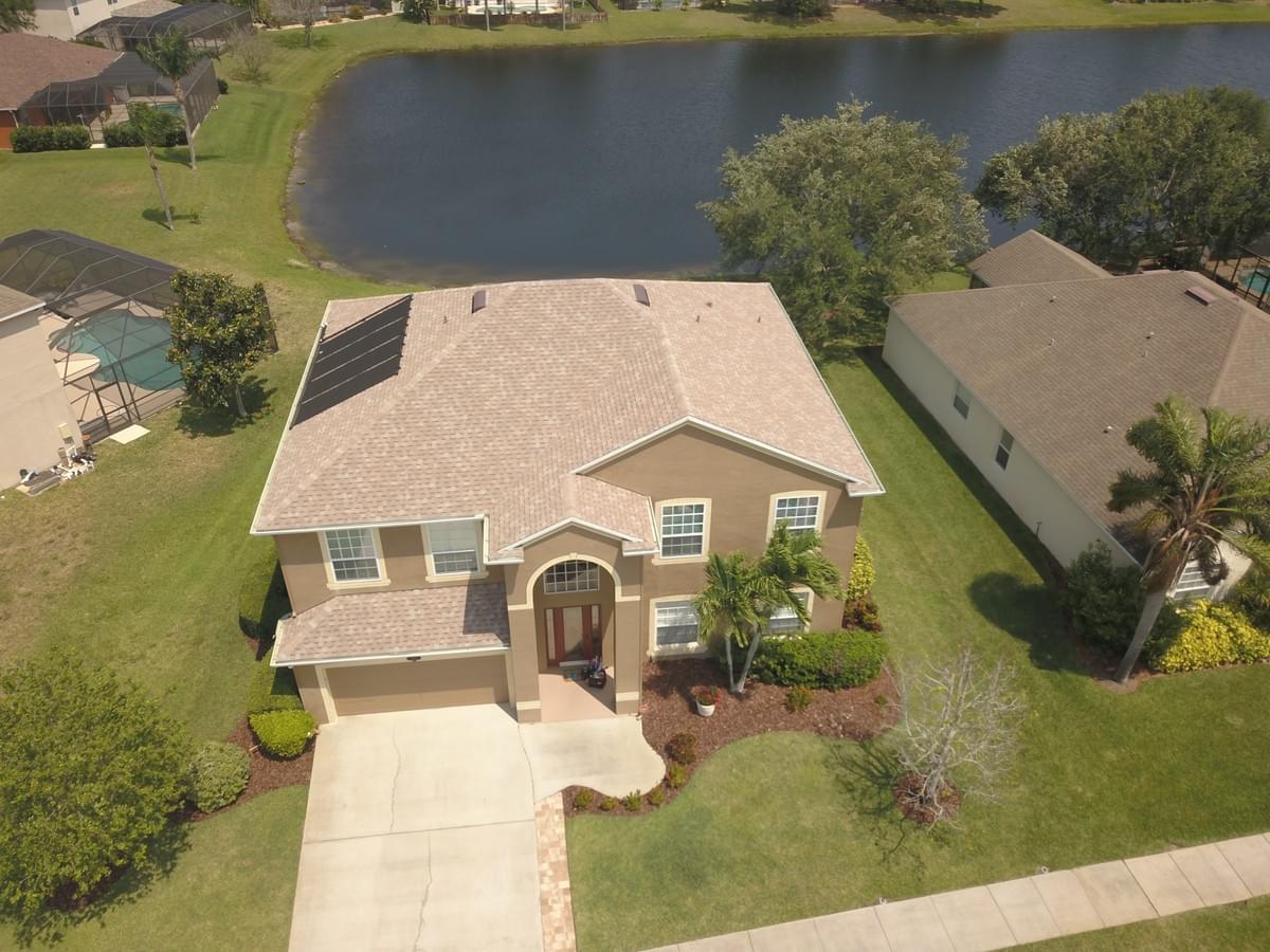 Aerial photo of 22 story tan home with brown accents.  Home is pictured in front of a lake. Aerial photo of 22 story tan home with brown accents.  Home is pictured in front of a lake.
