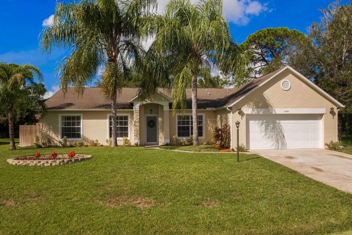 Tan home with multiple palm trees in the front Tan home with multiple palm trees in the front