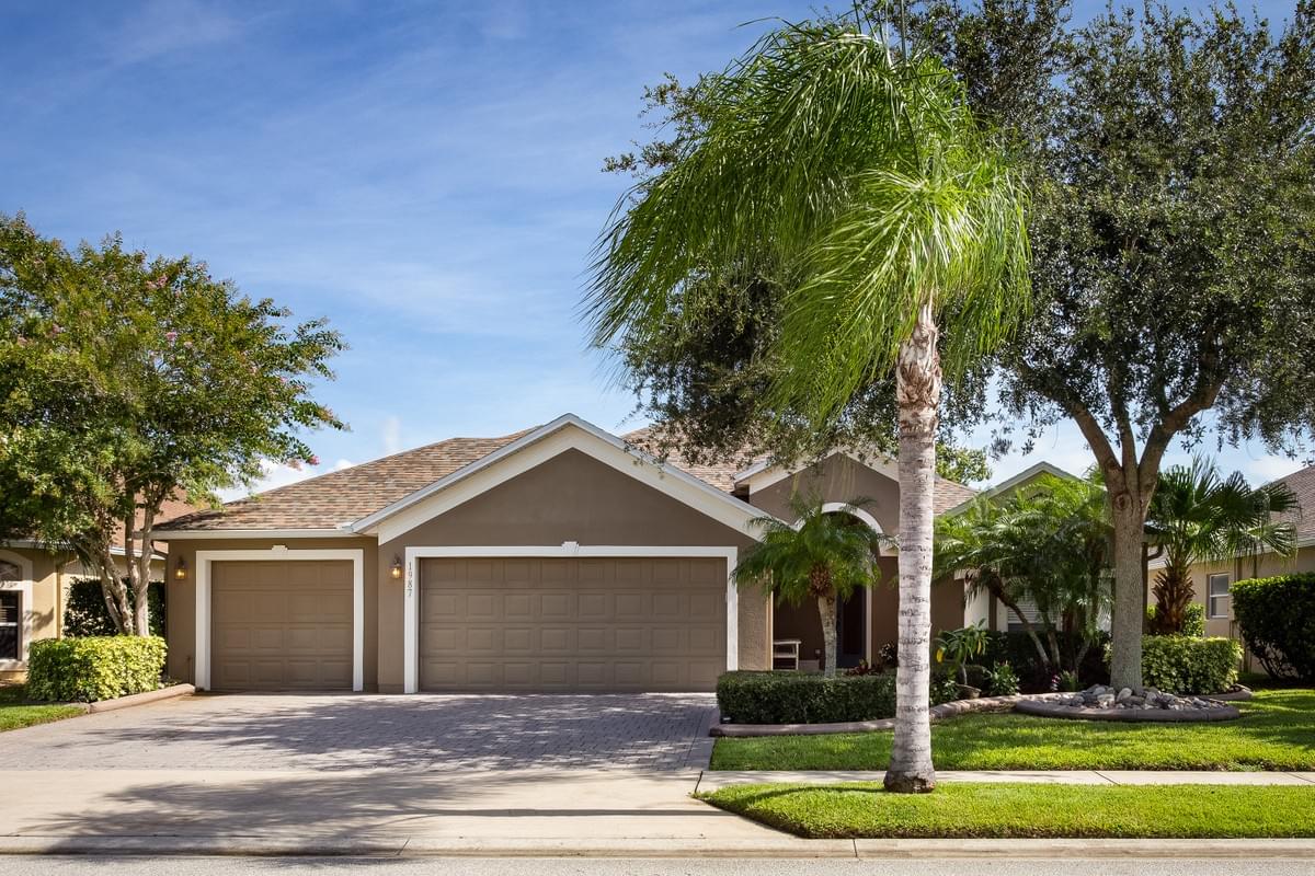 Brown home with 3 car garage with a large oak tree and palm tree in the front yard Brown home with 3 car garage with a large oak tree and palm tree in the front yard