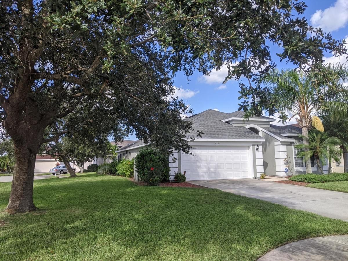 Light gray painted home with large mature trees on a corner lot Light gray painted home with large mature trees on a corner lot