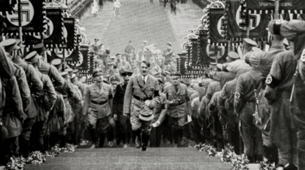 Historical photo of a Nazi parade showing the visual grammar of totalitarian power — a vertical choreography of domination, used here to illustrate Johann Chapoutot’s analysis of propaganda as a language. (En français :) Photographie historique d’un défilé nazi illustrant la grammaire visuelle du pouvoir totalitaire — une chorégraphie verticale de domination, utilisée ici pour illustrer l’analyse de Johann Chapoutot sur la propagande comme langage. Historical photo of a Nazi parade showing the visual grammar of totalitarian power — a vertical choreography of domination, used here to illustrate Johann Chapoutot’s analysis of propaganda as a language. (En français :) Photographie historique d’un défilé nazi illustrant la grammaire visuelle du pouvoir totalitaire — une chorégraphie verticale de domination, utilisée ici pour illustrer l’analyse de Johann Chapoutot sur la propagande comme langage.