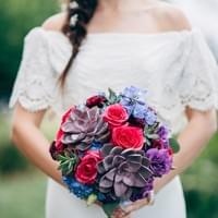 Textural bridal bouquet with purple succulents, hot pink roses, and blue flowers
