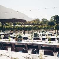 Farm style rustic wedding table layout with greenery and market lights