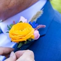 Yellow ranunculus boutonniere on classic blue suit