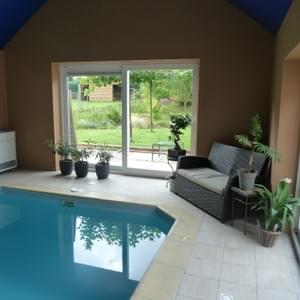 Piscine intérieure chauffée : vue sur la terrasse et le jardin