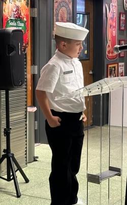 The youngest Sea Cadet proudly reading "Old Glory" at the Mount America Fundraising Dinner.