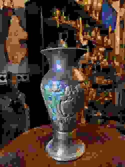 فازة معدنية قديمة الطراز مصنوعة من المعدن الثقيل، بتصميم أنيق وقاعدة ثابتة، مزينة بنقوش بارزة