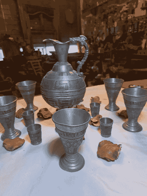 تقم زنك فاخر مصنوع يدوياً، يتكوّن من إبريق مركزي أنيق مع مجموعة كؤوس متناسقة بأحجام مختلفة،