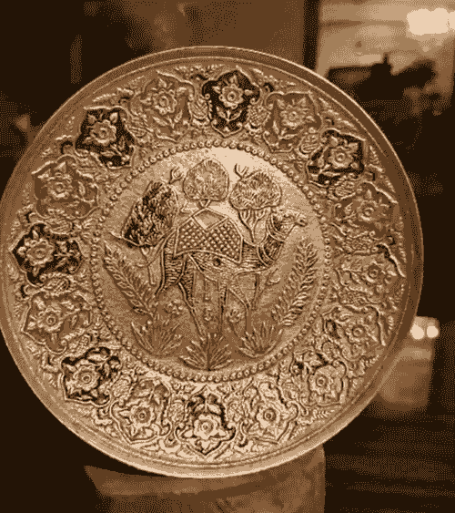 صحن ديكور نحاسي مزخرف بنقش يدوي فني مميز، يتوسطه جمل مزخرف بتفاصيل دقيقة ومحاط بزخارف زهرية ملونة