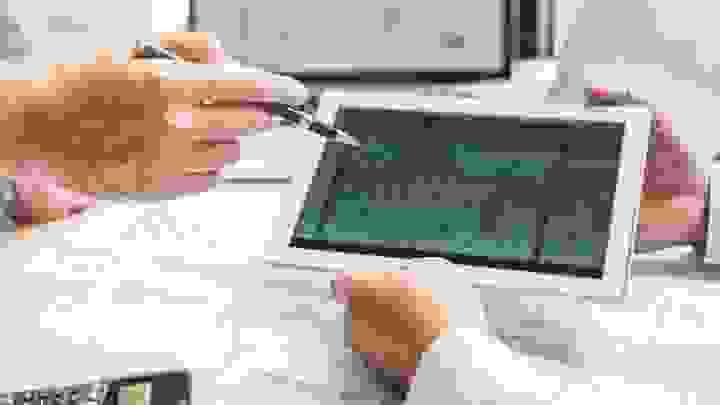 Architectural drawings on a table, rolled out with a ruler across them, and a 3D frame of a large building projecting out of the drawings Architectural drawings on a table, rolled out with a ruler across them, and a 3D frame of a large building projecting out of the drawings