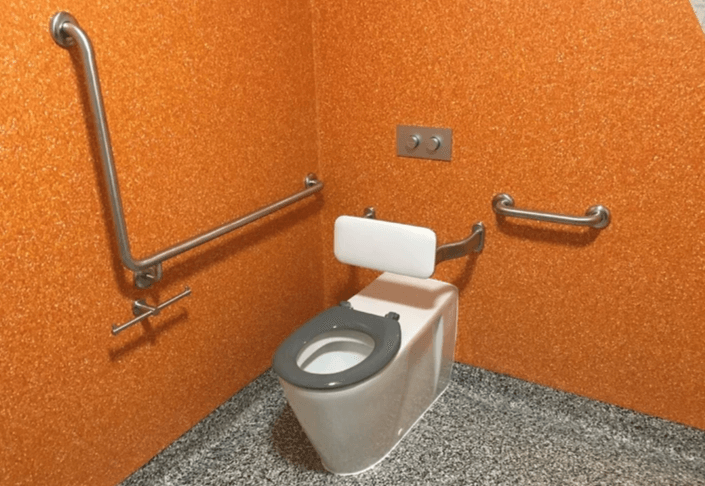 A man is seated at a desk, using a laptop and writing notes into a notebook