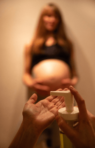 massageolie die op hand word gedaan om een zwangere vrouw te masseren