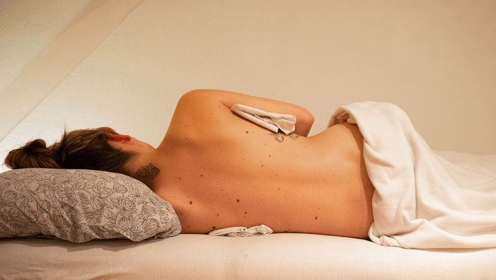 rug van een zwangere vouw op massage tafel in zijligging