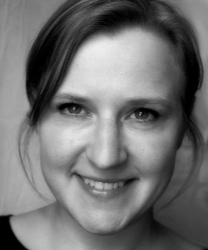 Czarno- białe zdjęcie szeroko uśmiechniętej młodej kobiety ze związamymi włosami 