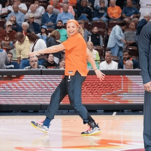 Rachel mimes like she is walking in orange warmups