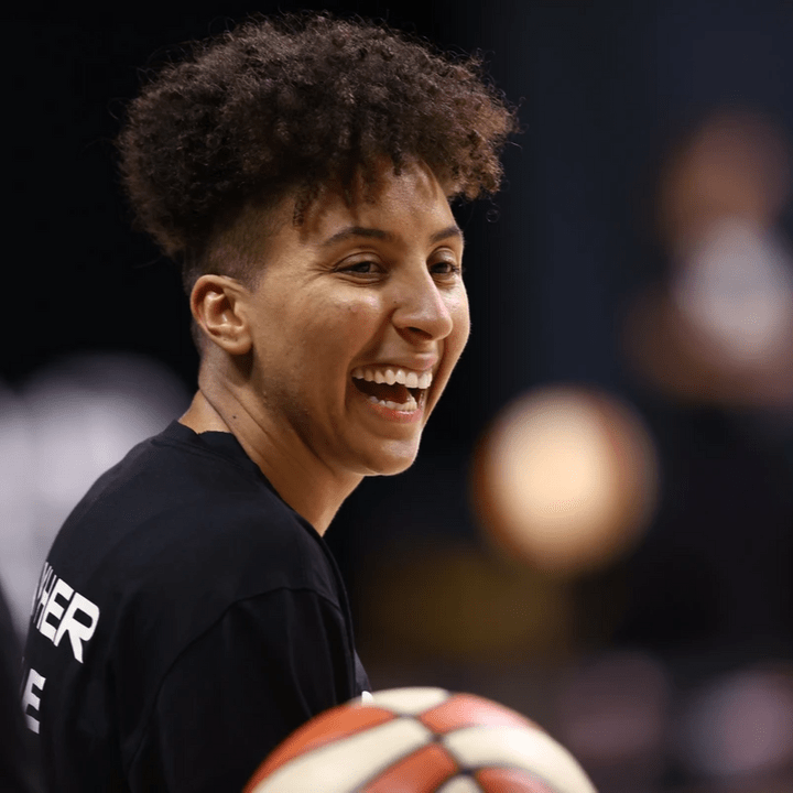 Layshia smiles with basketball in foreground