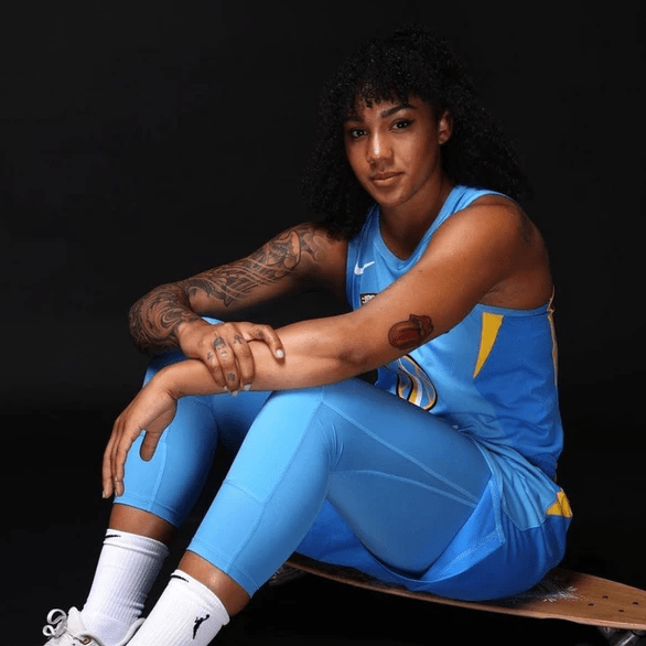 Gabby sits on longboard in Chicago Sky uniform