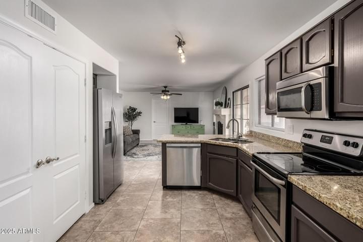 Updated kitchen with granite countertops and stainless steel appliances in Val Vista Lakes home for sale.