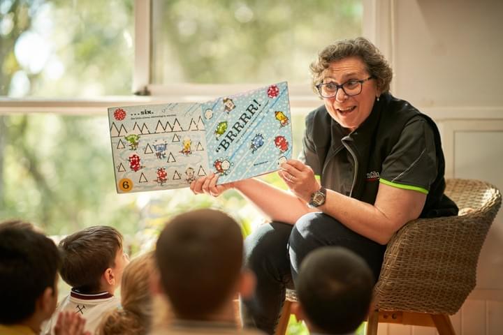 Educator reading a picture book to children at Fern Gully Educator reading a picture book to children at Fern Gully