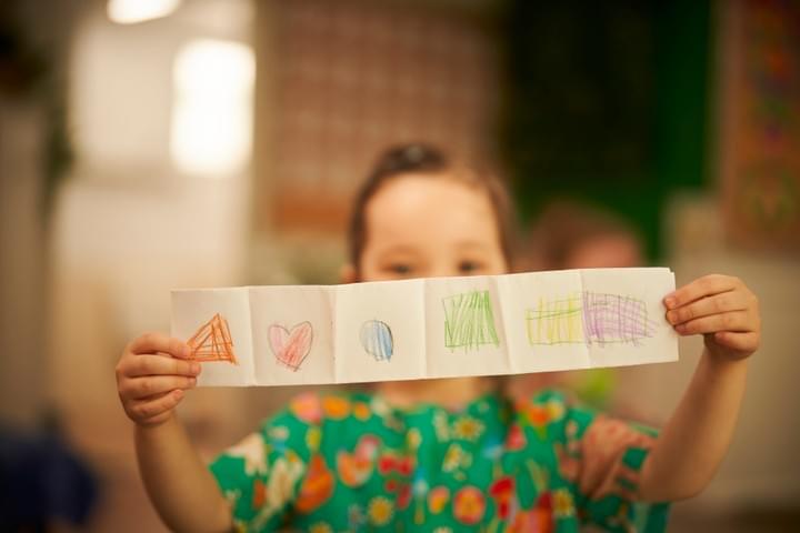 Child proudly showing their drawing