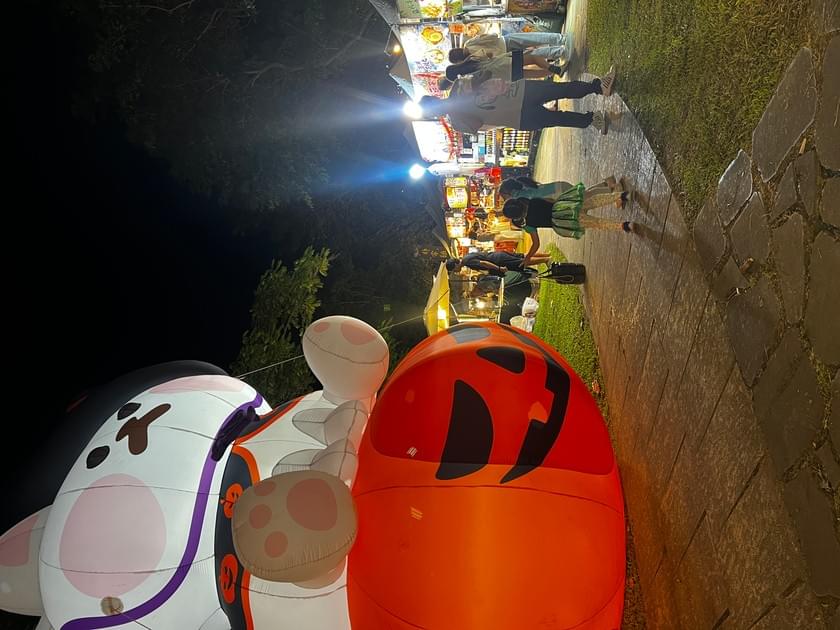 大型貓咪與南瓜充氣裝置成為現場視覺焦點,步道旁可見夜間攤位。