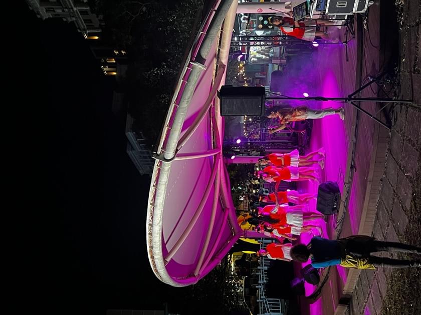 棚架舞台以紫紅色燈光照明,表演者在台上演出。