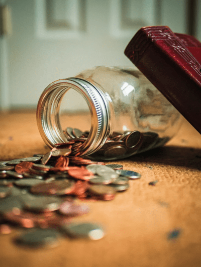 Assorted coin lot in a clear glass jar on a wooden table