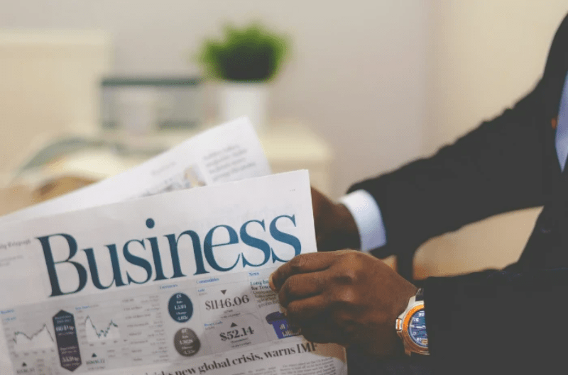 business man holding newspaper opened on stock market page
