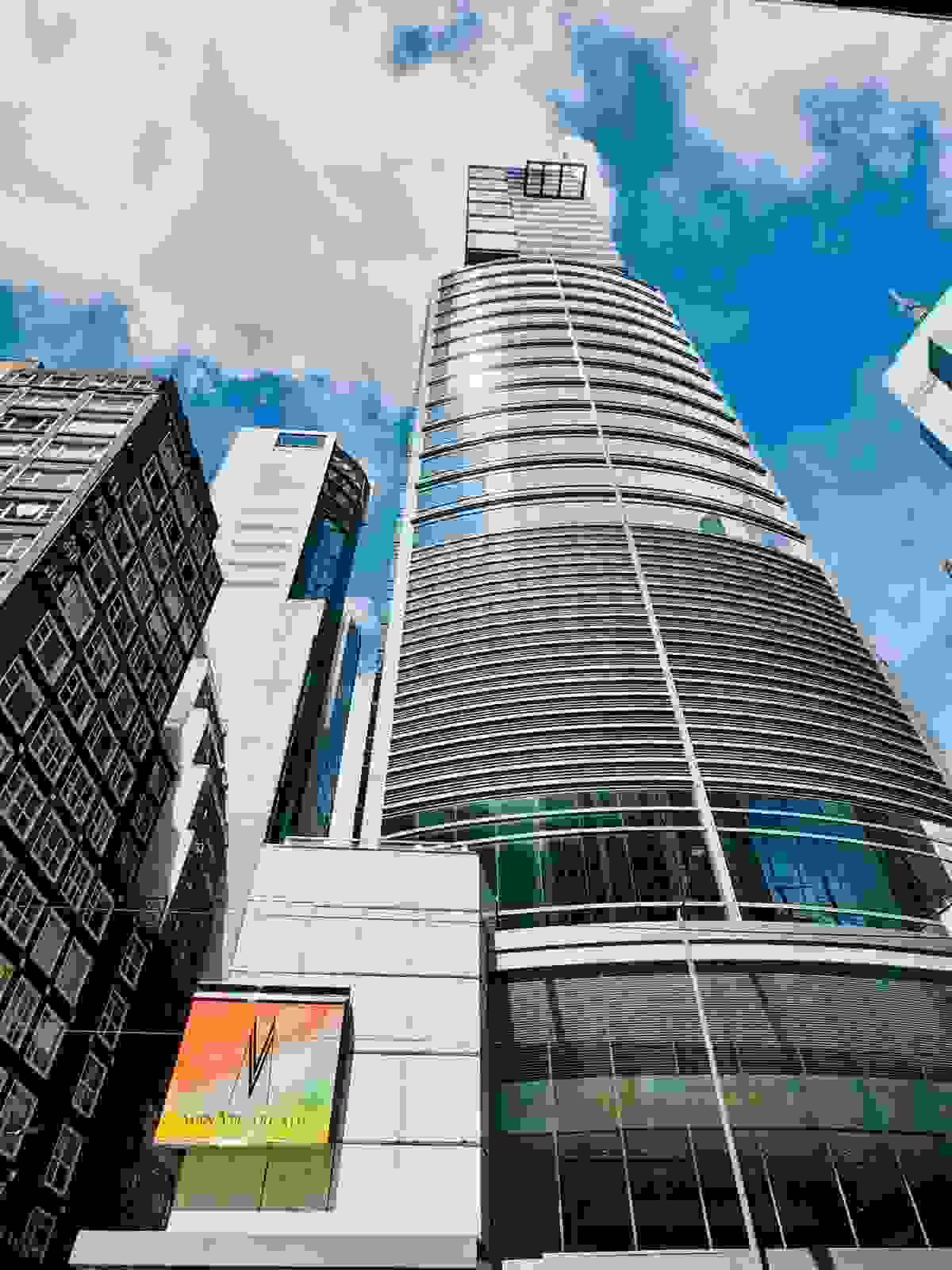 Street-level view looking up at the modern 35-storey glass tower of Man Yee Building, Central Hong Kong, with Man Yee Arcade signage at the base under a bright sky