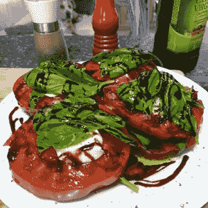 Cherokee Purple beefsteak heirloom tomato cut to show dusky rose hues, whole fruit blurred in background, grown chemical-free in Hokianga, Northland, New Zealand. Cherokee Purple beefsteak heirloom tomato cut to show dusky rose hues, whole fruit blurred in background, grown chemical-free in Hokianga, Northland, New Zealand.