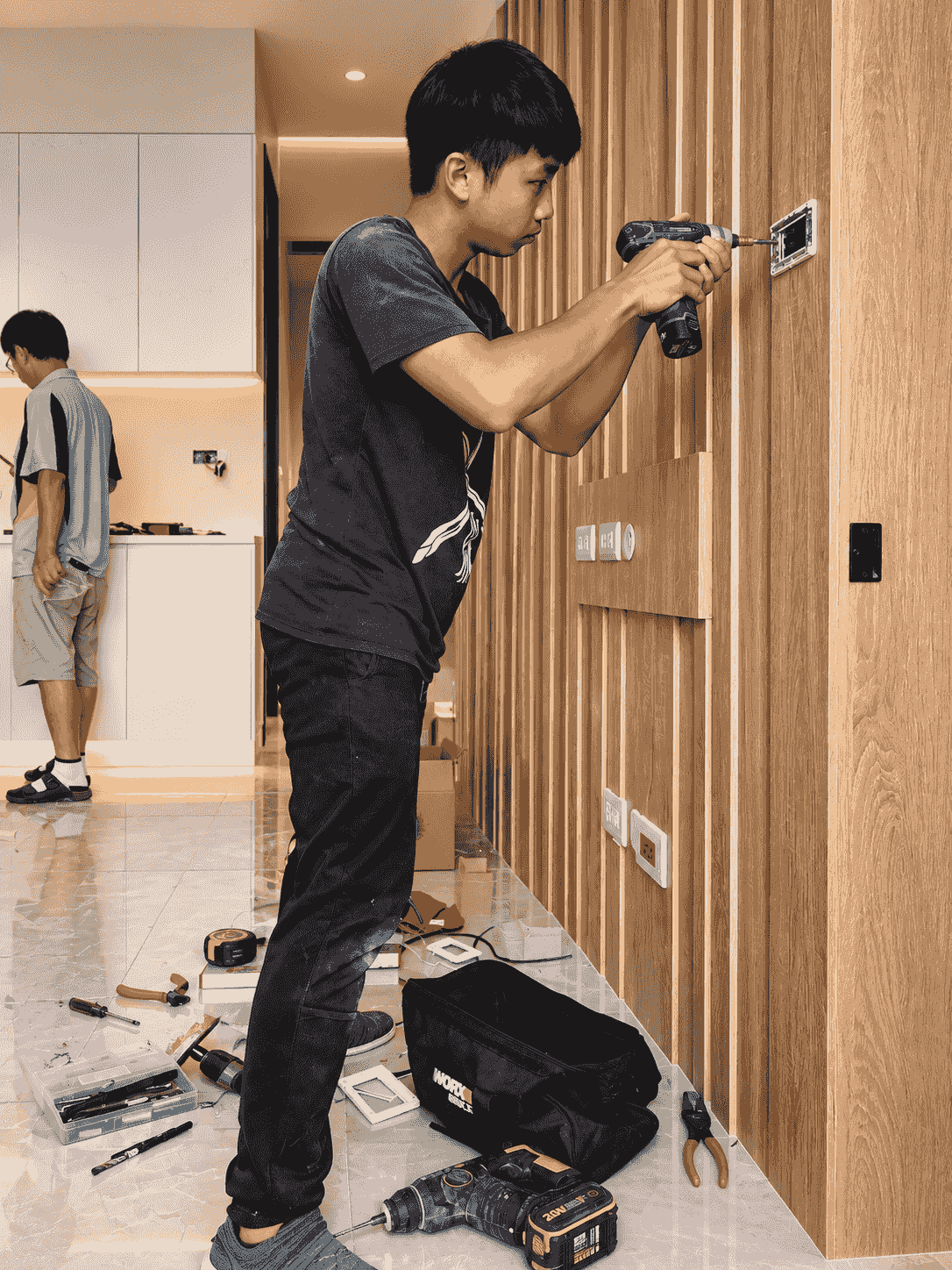 水電師傅在桃園木作造型牆面旁,使用電動螺絲起子精準安裝開關插座面板。 水電師傅在桃園木作造型牆面旁,使用電動螺絲起子精準安裝開關插座面板。