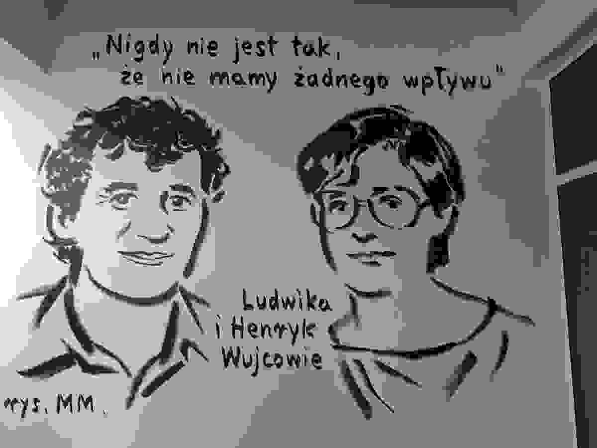 Mężczyzna i kobieta, młodzi.  Głównie twarze i zarysy ramion. On ma kędzierzawe włosy, ona ktrótko obcięte, nosi okulary. Nad nimi napis "Nigdy nie jest tak, że nie mamy żadnego wpływu". Pomiędzy nimi napis "Ludwika i Henryk Wujcowie".  W lewym dolnym rogu podpis rys.  MM.