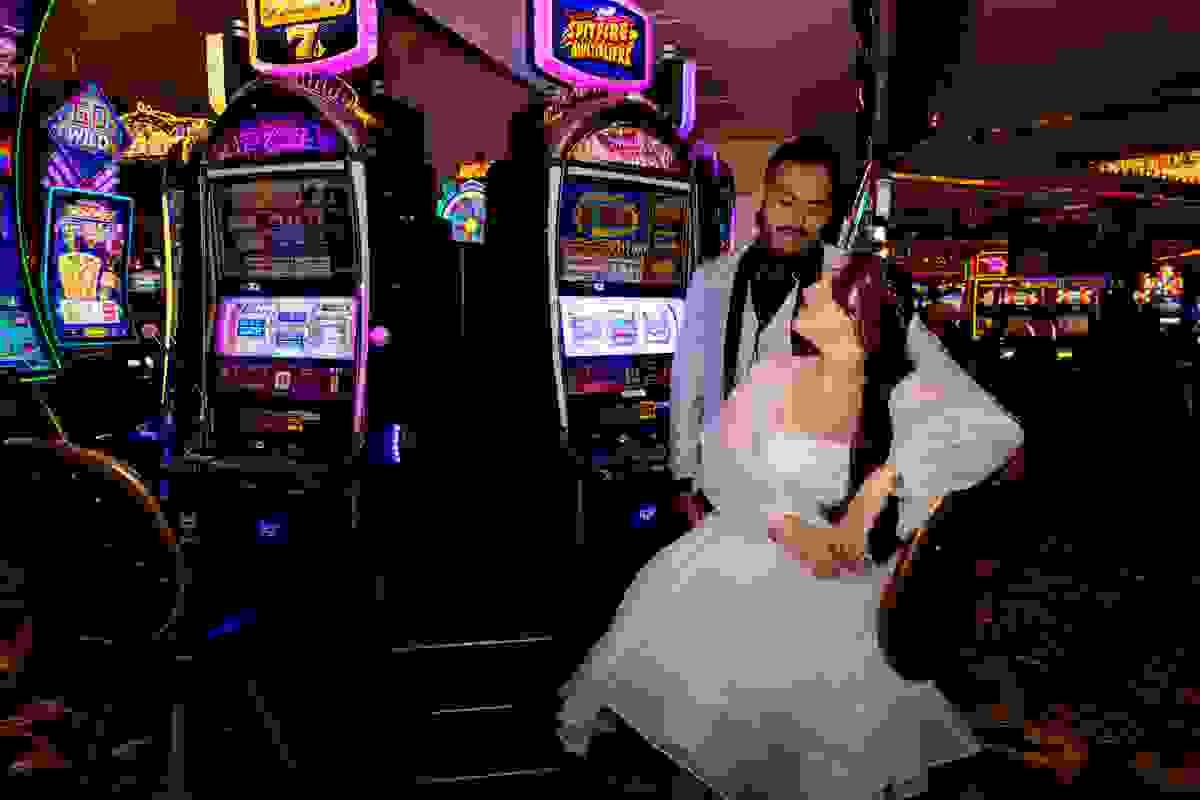 Couple smiling and posing together inside a Las Vegas casino, capturing the vibrant gaming and wedding atmosphere.