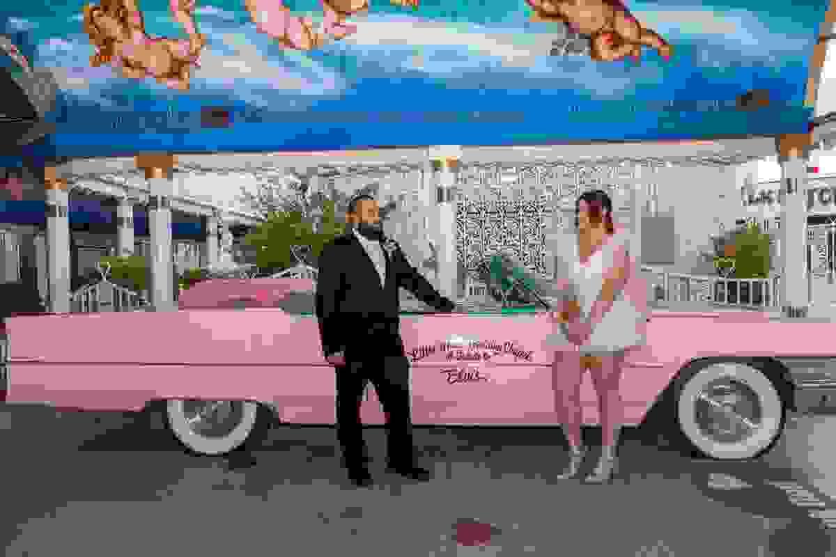 Couple posing outside the iconic pink Little White Wedding Chapel in Las Vegas