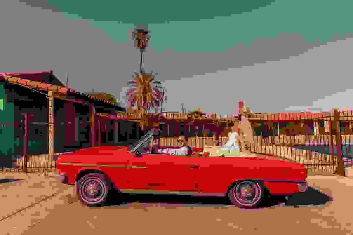 Newlywed couple sitting in a vintage red Cadillac outside Sure Thing Chapel in Las Vegas during their Drive Thru wedding.