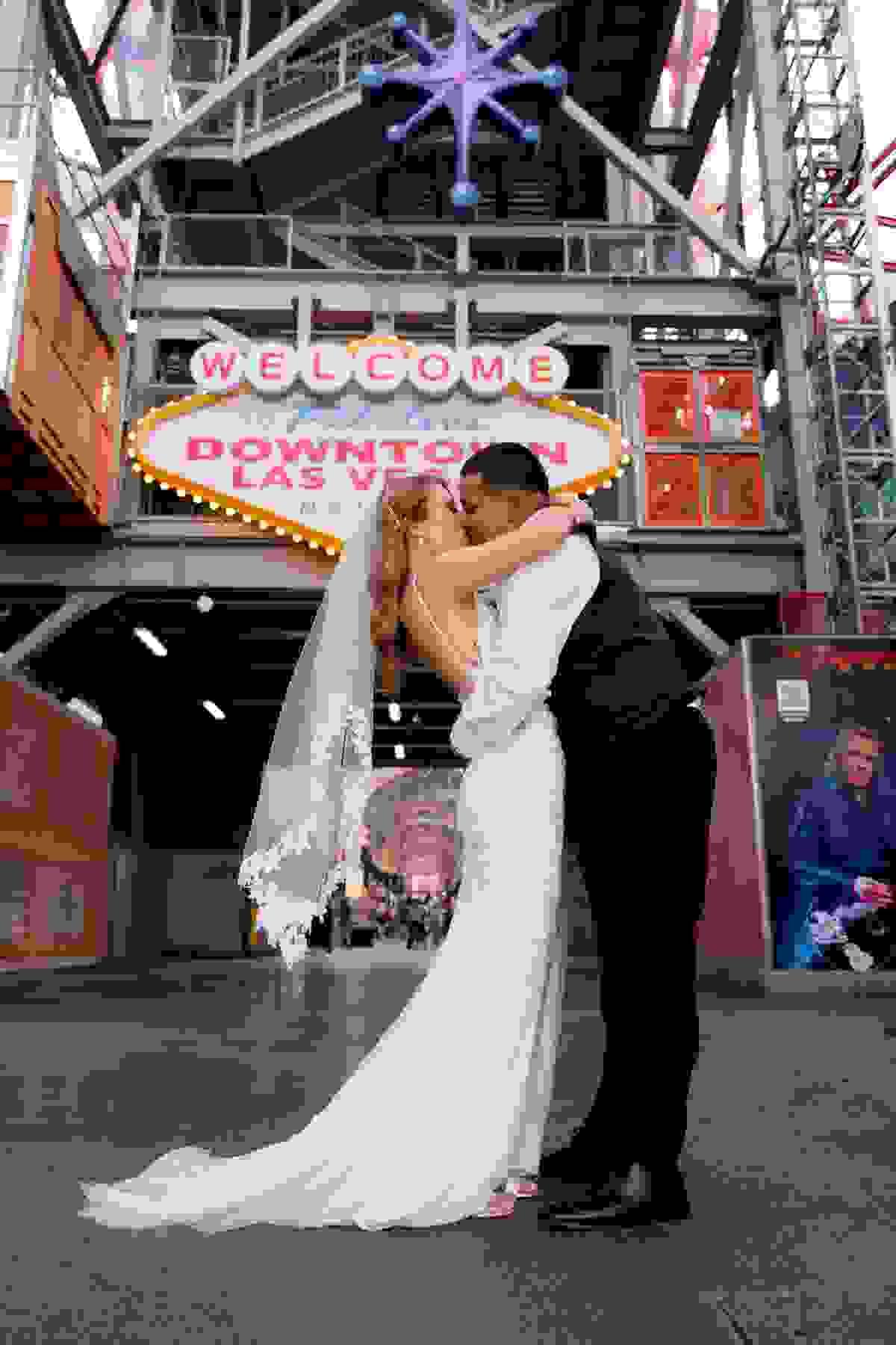 Couple sharing a kiss in front of the iconic Welcome to Las Vegas sign on Fremont Street during their same-day elopement.