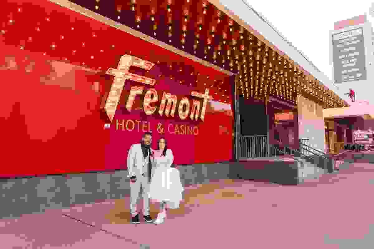 Couple posing in front of the Fremont Hotel on Fremont Street, capturing the vintage Las Vegas neon vibe.